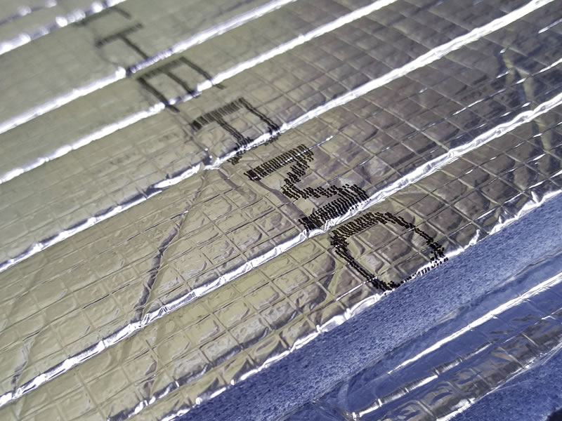 Cross-section close-up ของ Thermobreak LS — เห็นพิมพ์ THERMOBREAK LS บน foil + โครงสร้าง closed-cell foam